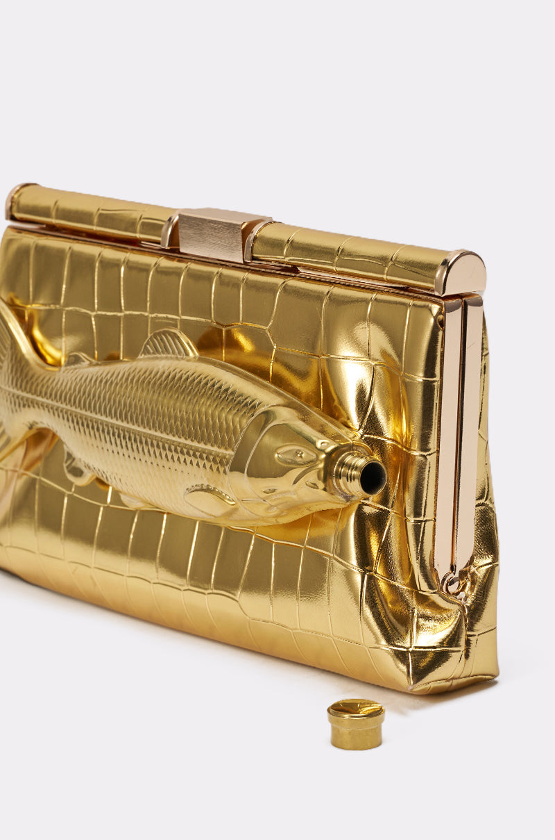 The GONE FISHIN CLUTCH is a gold croc-embossed bag featuring a raised fish design, a circular mouth opening with cap, and a removable crossbody chain for versatile styling. 6