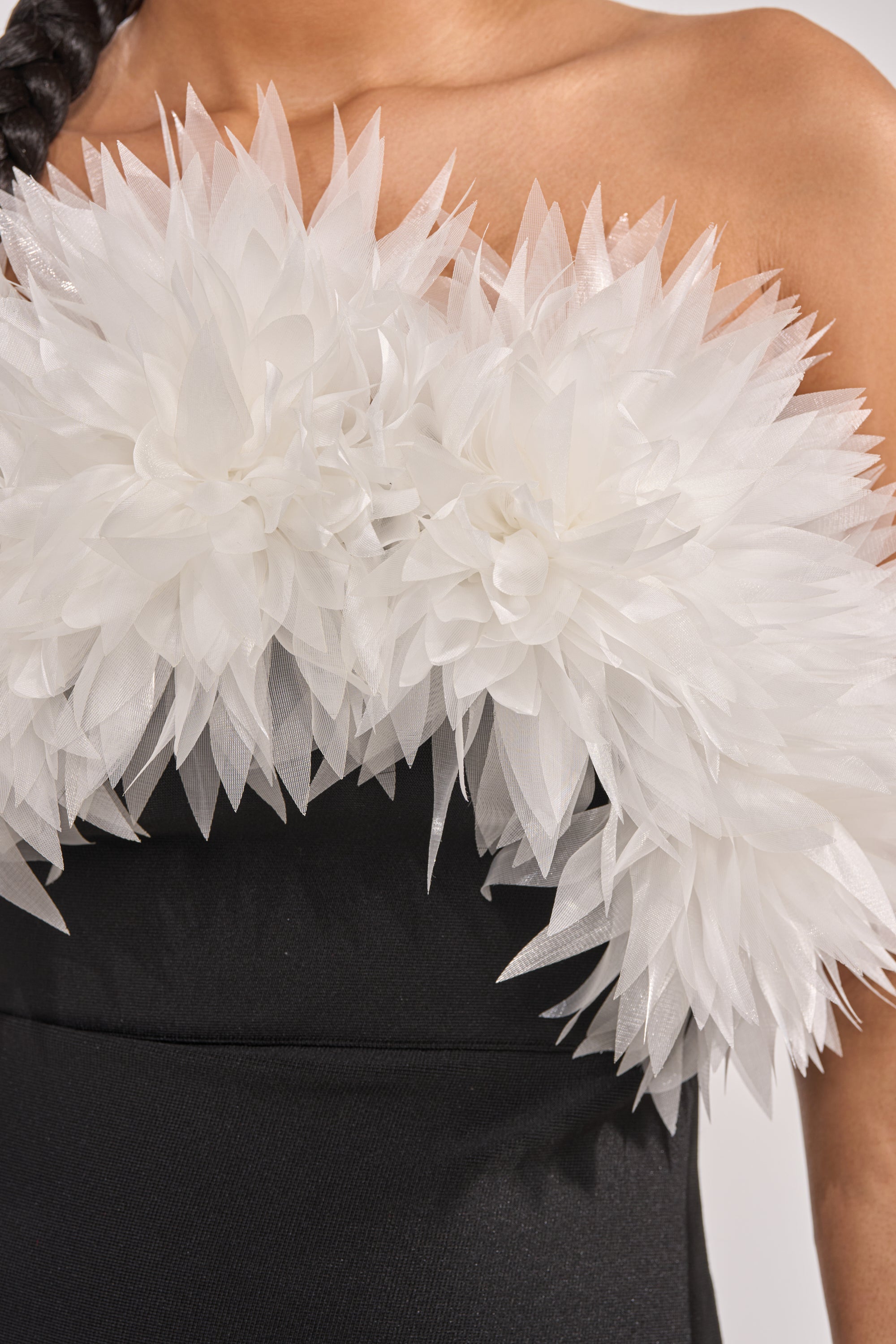 A close-up of the HEART ON MY SLEEVE BANDAGE MIDI DRESS IN BLACK highlights large white sheer floral appliqués across the chest, making it an elegant strapless choice for evening wear. 4