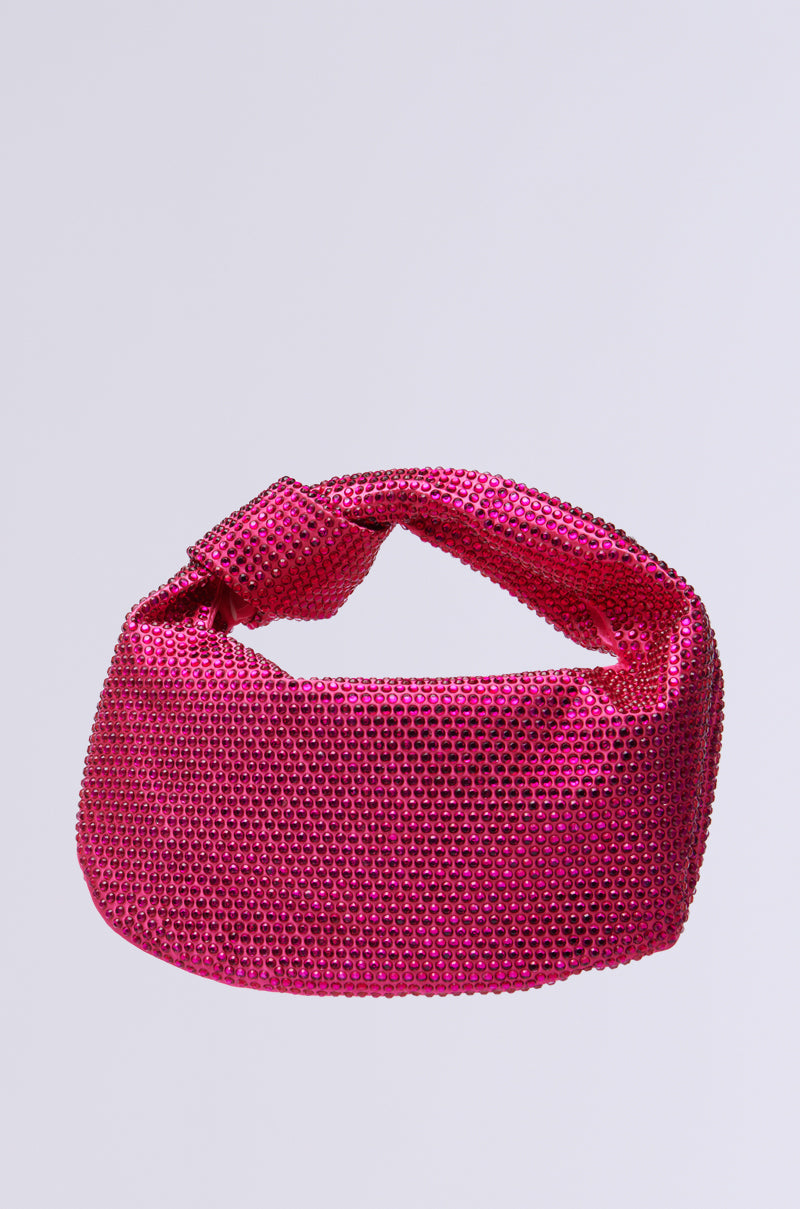 Against a plain gray backdrop, the pink RAZZLE DAZZLE BLING PURSE shines with its textured surface, rhinestone embellishments, rounded top handle, and structured rectangular shape.
