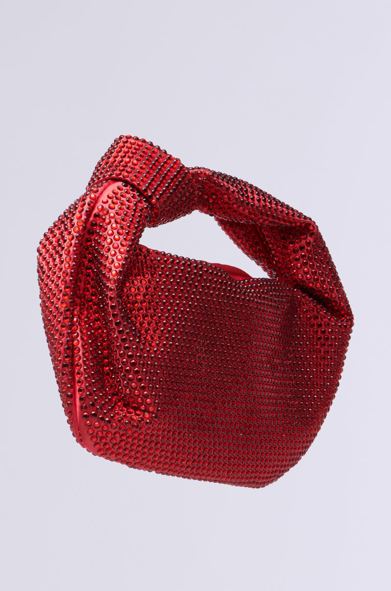 Meet the GLITZ AND GLAM BLING PURSE, a dazzling red handbag with rhinestone embellishments and a unique twisted handle. With its modern, rounded shape, this purse is ideal for your night out and pops perfectly against a light gray background.