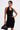 A person with short dark hair and tattoos wears the EDGY AND COOL LACE UP KNIT MINI DRESS, featuring black knit fabric with silver grommets, styled with silver earrings and a black handbag against a plain white background.