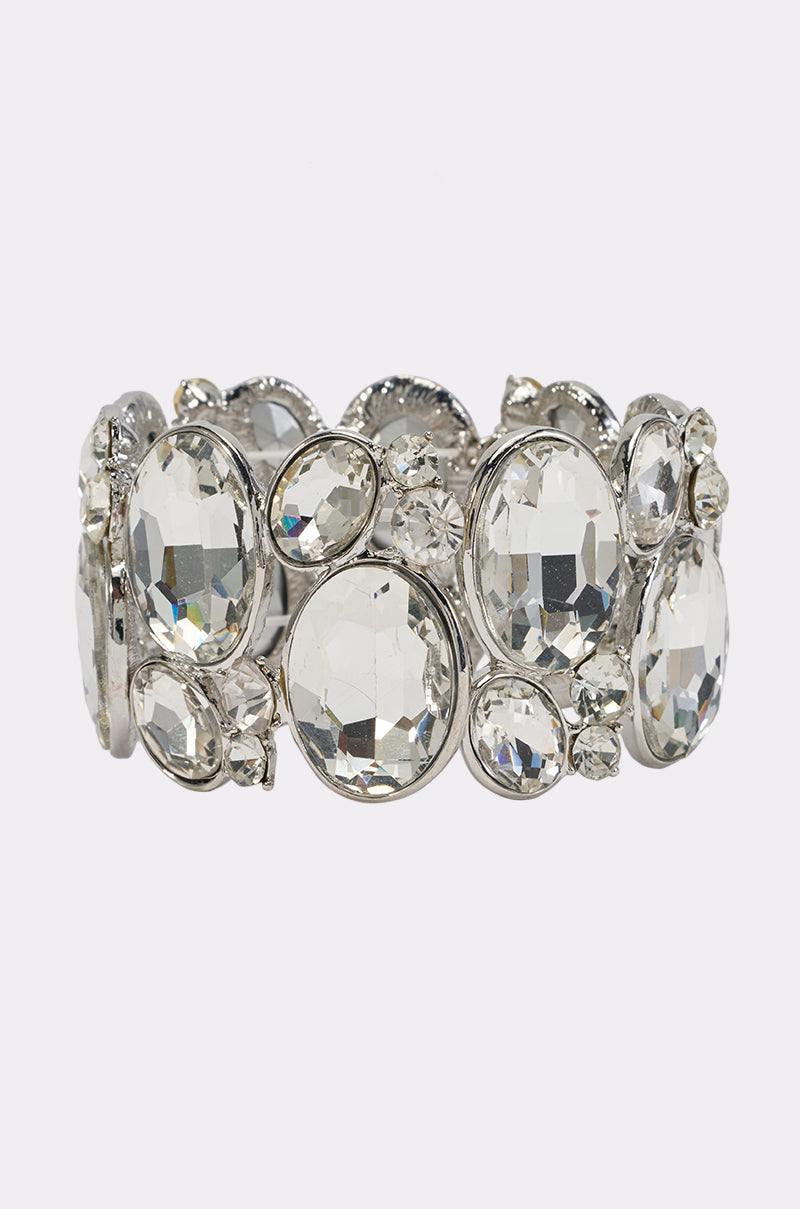 Introducing the CRYSTAL STRETCH BRACELET: a statement silver cuff adorned with clusters of large and small oval and round clear gemstones, designed to dazzle with sparkling crystal accents for an effortlessly elegant look.
