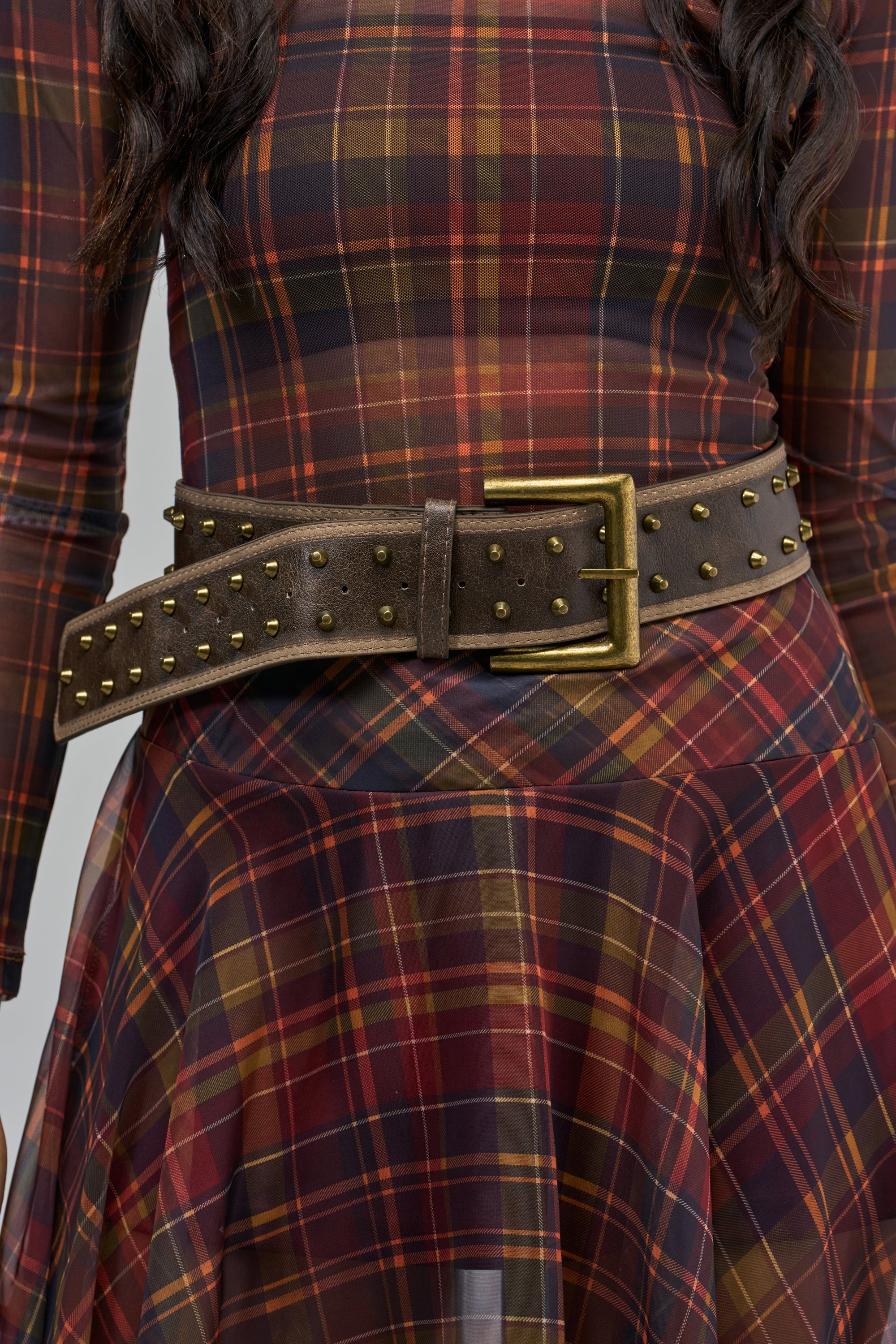 TENNESSEE STUDDED BELT in washed brown faux leather with gold-tone accents and a rectangular buckle, worn over a red and brown plaid dress.