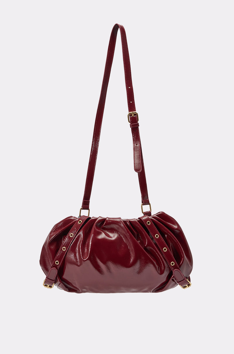 THEE BURGUNDY Y2K RUCHED PURSE is a dark red faux patent leather shoulder bag with gold hardware and an adjustable crossbody strap, shown against a light background. 3