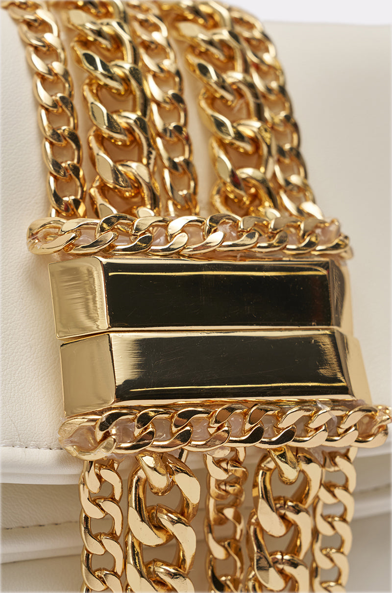 Close-up of the KIMMY CLUTCH, featuring a shiny gold chain with a rectangular clasp detail attached to white faux leather, highlighting its elegant design for an evening out. 3