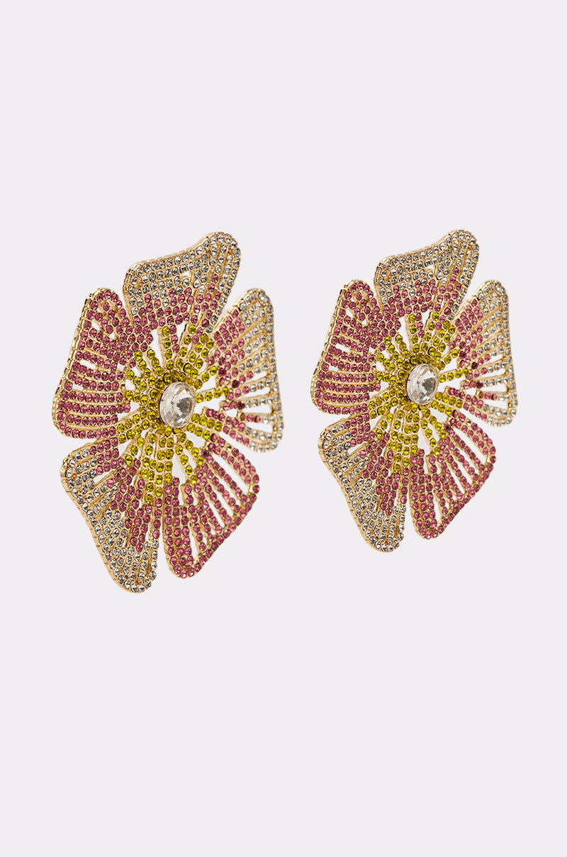 The IM JUST PRETTY EARRING is a pair of flower-shaped statement earrings with pink, yellow, and clear rhinestones and a large central clear stone, displayed on a plain white background. 2