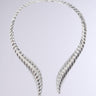 The TOO TUFF NECKLACE is presented against a plain background, showcasing its silver twisted torc design with open ends from the AKIRA Label. This statement jewelry piece boasts intricate spirals along its length, offering a sophisticated and elegant look that emphasizes its metallic silver sheen.