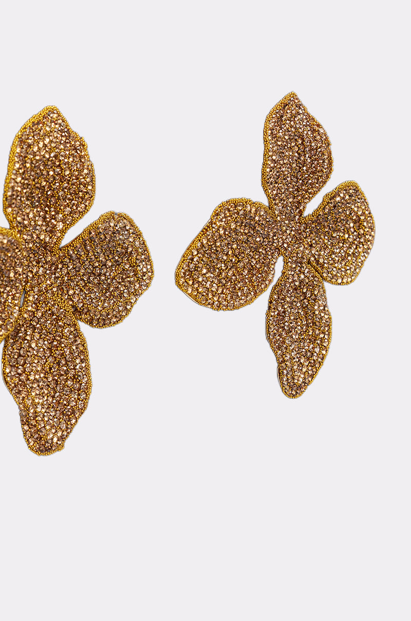 The GOLDEN GLAM EARRING features two sparkling, textured gold statement earrings with four petals each, shown on a plain white background. 3