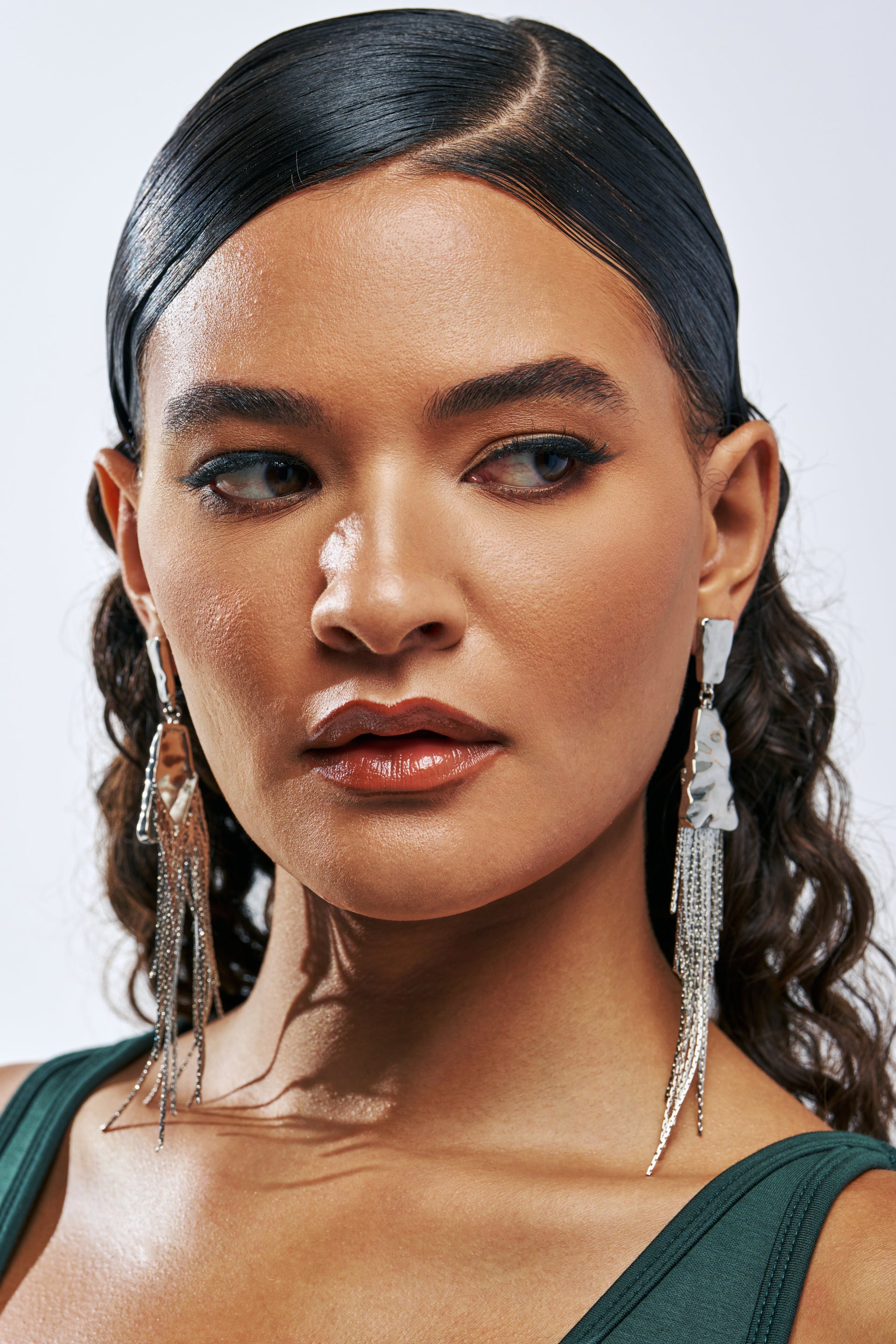 A person wearing silver FEELING EXTRA DANGLE FRINGE EARRINGS featuring a textured metal top piece and cascading fine silver chains.
