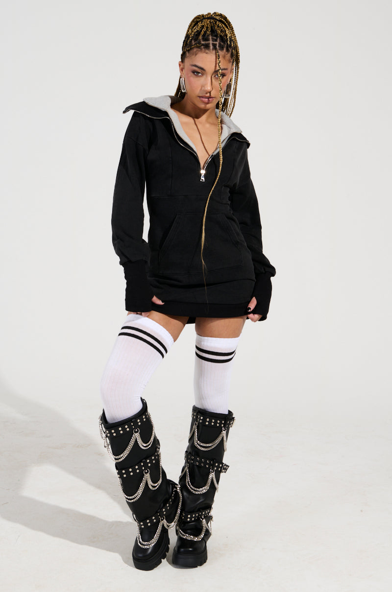 A person with braided hair is wearing a black zip-up hoodie, a white top, ULTIMATE THIGH HIGH SOCKS featuring varsity stripes, and black boots adorned with silver chains. The background is plain white. 1