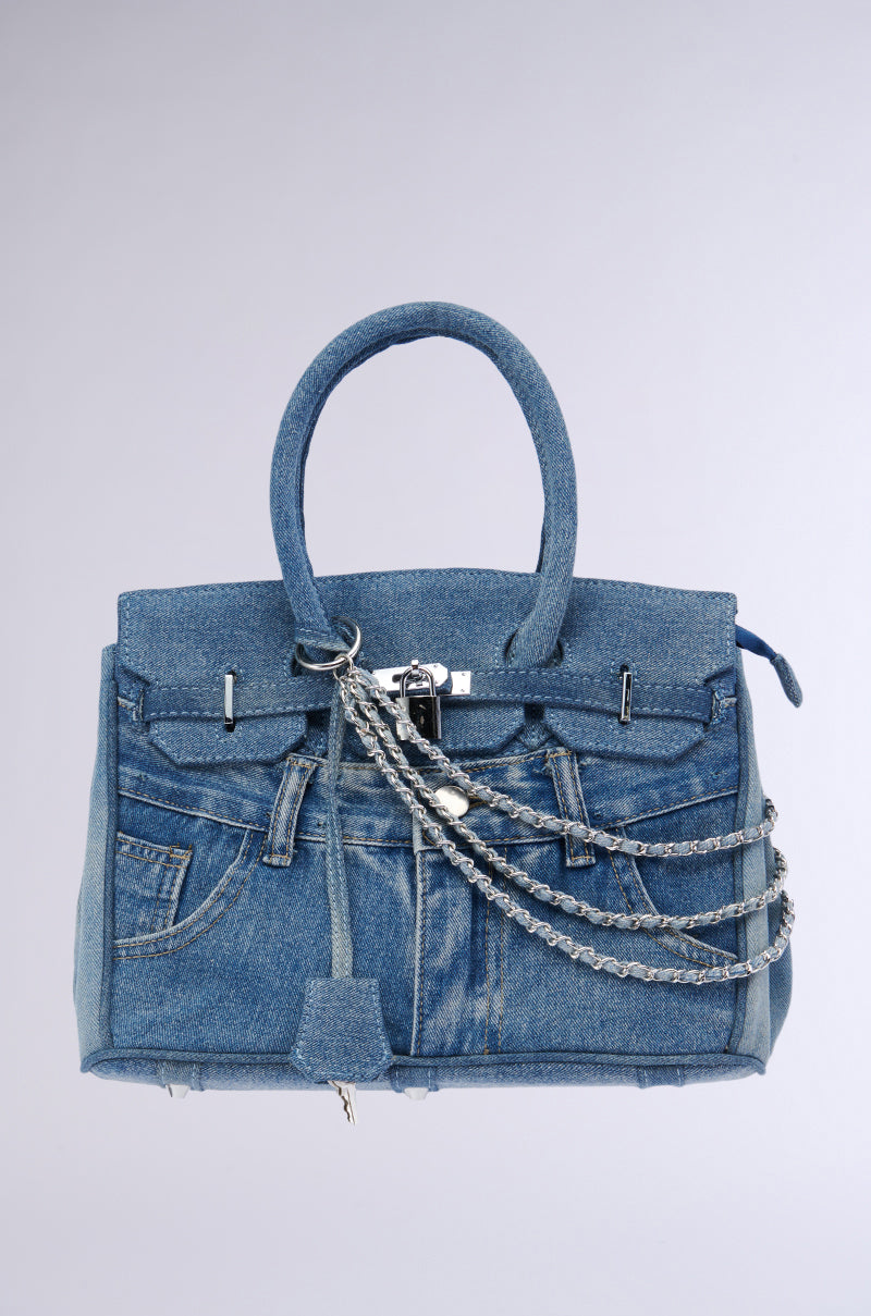 A close-up view of the DENIM BLUES TOTE PURSE designed to look like denim jeans. The bag features handles, a front pocket resembling jean pockets, and visible silver hardware draped across the front. The background is a plain white to light gray gradient.