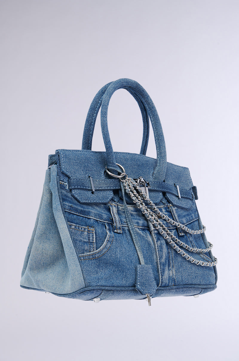 Introducing the Denim Blues Tote Purse, a stylish handbag crafted to resemble blue denim jeans. It features front pockets, belt loops, and silver hardware draped across the front. The purse boasts a jean waistband design and includes a top handle, set beautifully against a plain background.
