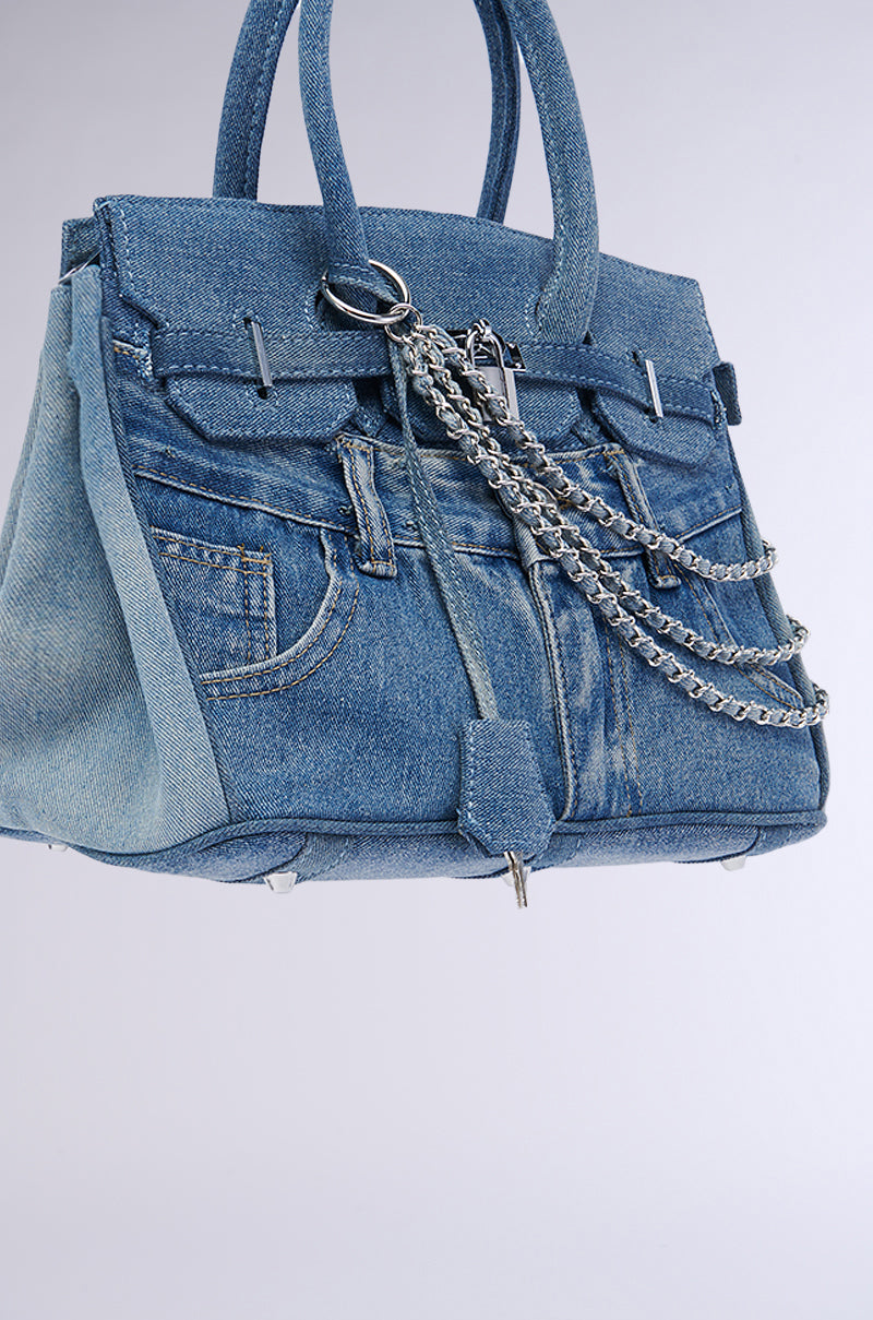 The DENIM BLUES TOTE PURSE is designed to resemble denim jeans, featuring prominent front pockets, belt loops, and metal button details. Adorned with silver hardware and dual handles for carrying, this purse combines light and dark blue denim for a stylish and casual appearance.