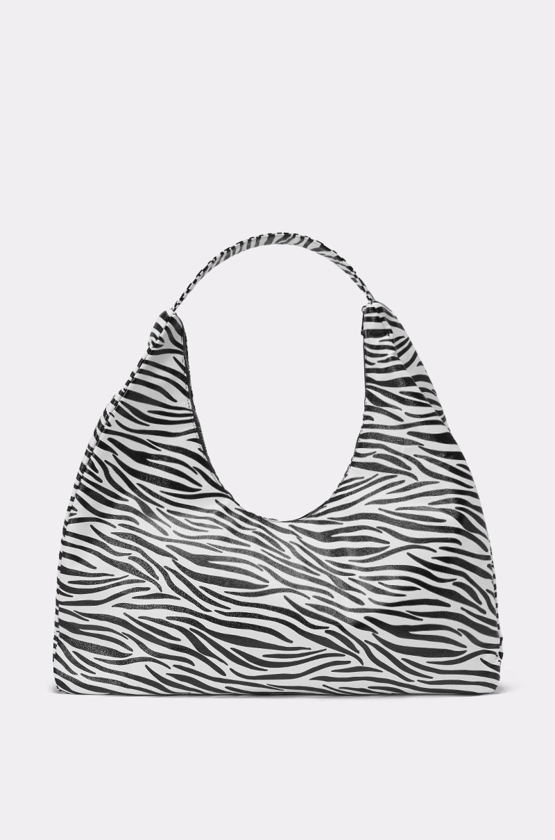 The IN THE WILD OVERSIZED TOTE is a large faux leather bag with a black and white zebra print, wide curved opening, and single matching handle, shown against a plain light gray background. 0