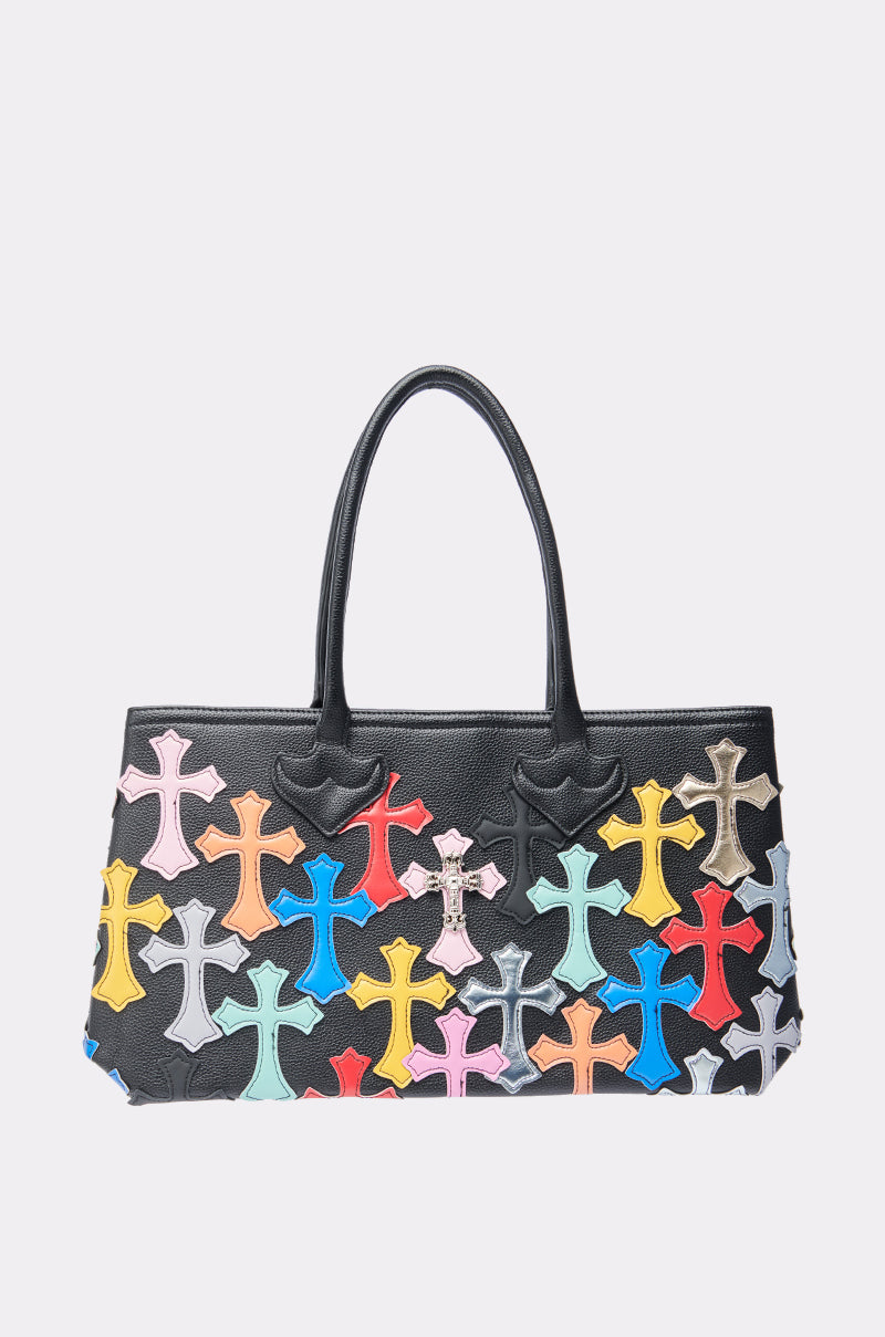 The PERSONAL PROBLEM CROSS TOTE is a black handbag with double handles, featuring colorful cross-shaped patches in red, yellow, blue, pink, and gray that cover the entire front.