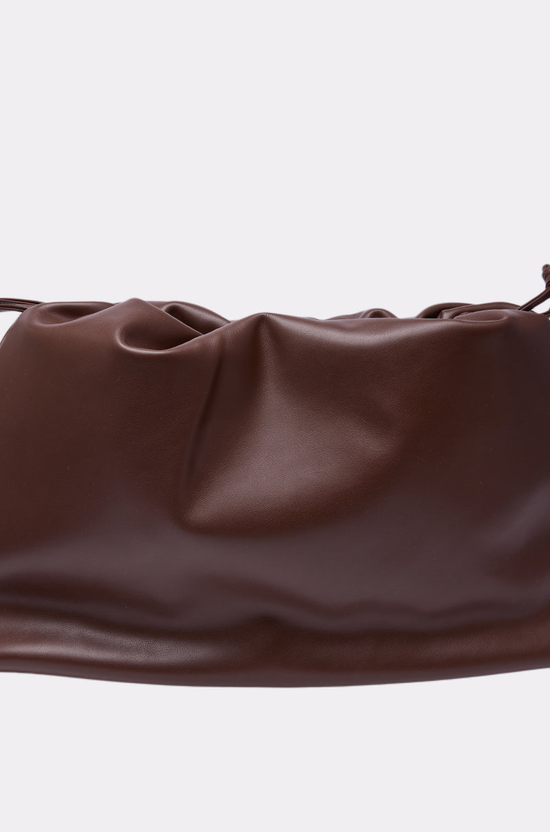 A close-up of the IN PARIS WITH IT PURSE, a soft brown minimalist clutch with a gathered ruched top, shown against a plain white background. 6