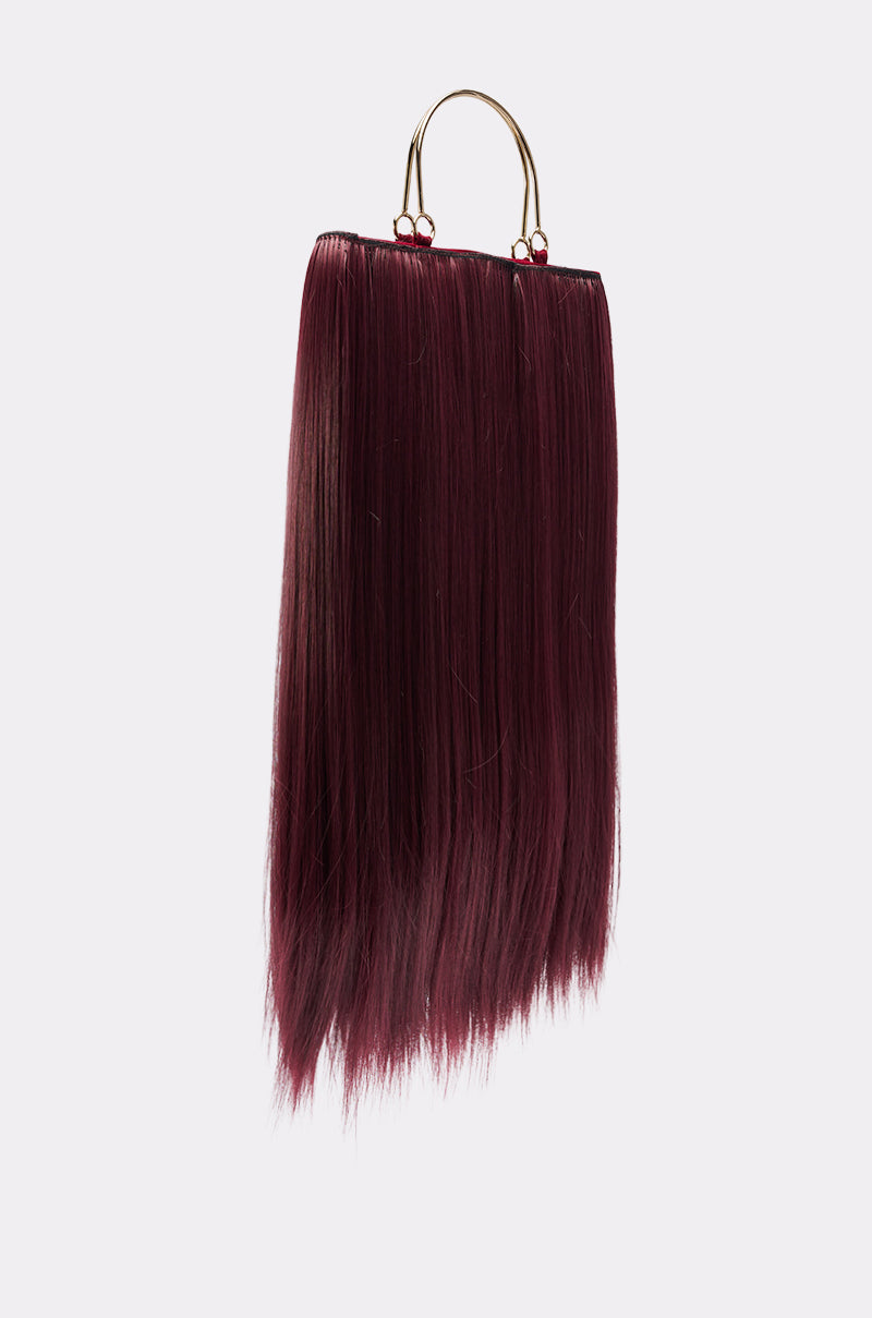 A maroon straight hair extension with a gold clip hangs against a plain light background—an accessory as chic as the MY HAIR PURSE.