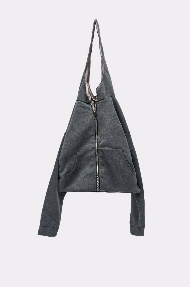 The CARRY ME HOODIE PURSE, a dark gray zip-up bag with front pockets, hangs by its hood against a plain light background. With sleeves draping loosely, it’s perfect for street style or as a functional everyday accessory.