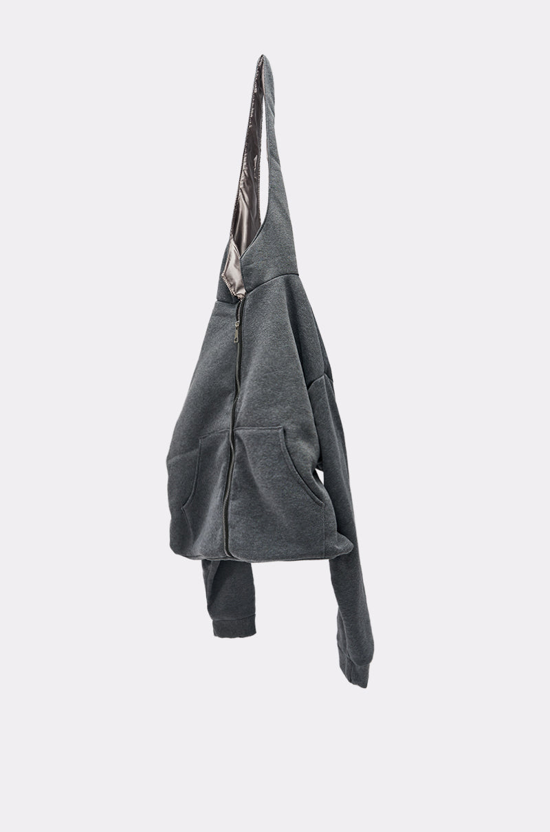 The CARRY ME HOODIE PURSE, a dark gray zip-up hoodie with front pockets and street-inspired style, hangs on a hook against a plain light gray background.
