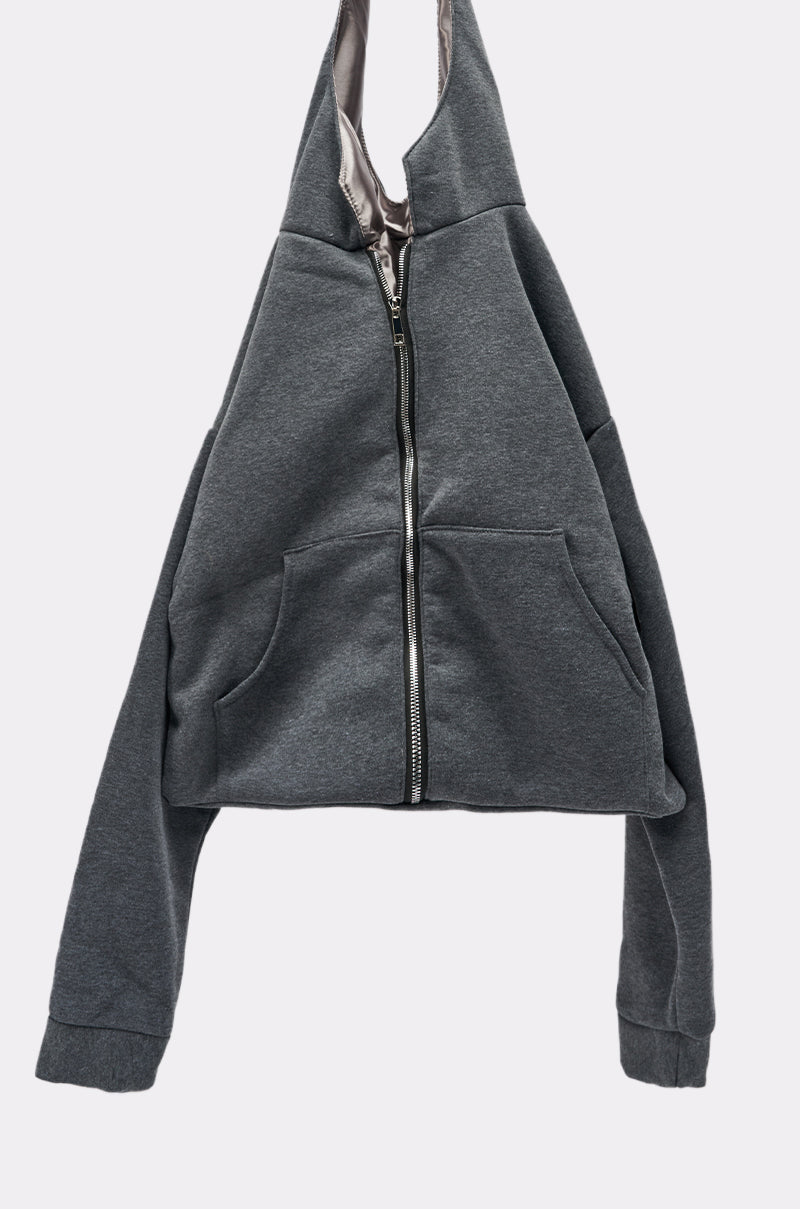The CARRY ME HOODIE PURSE, a dark gray zip-up hoodie-inspired purse with front pockets and streetwear flair, hangs on a hook against a plain light background.
