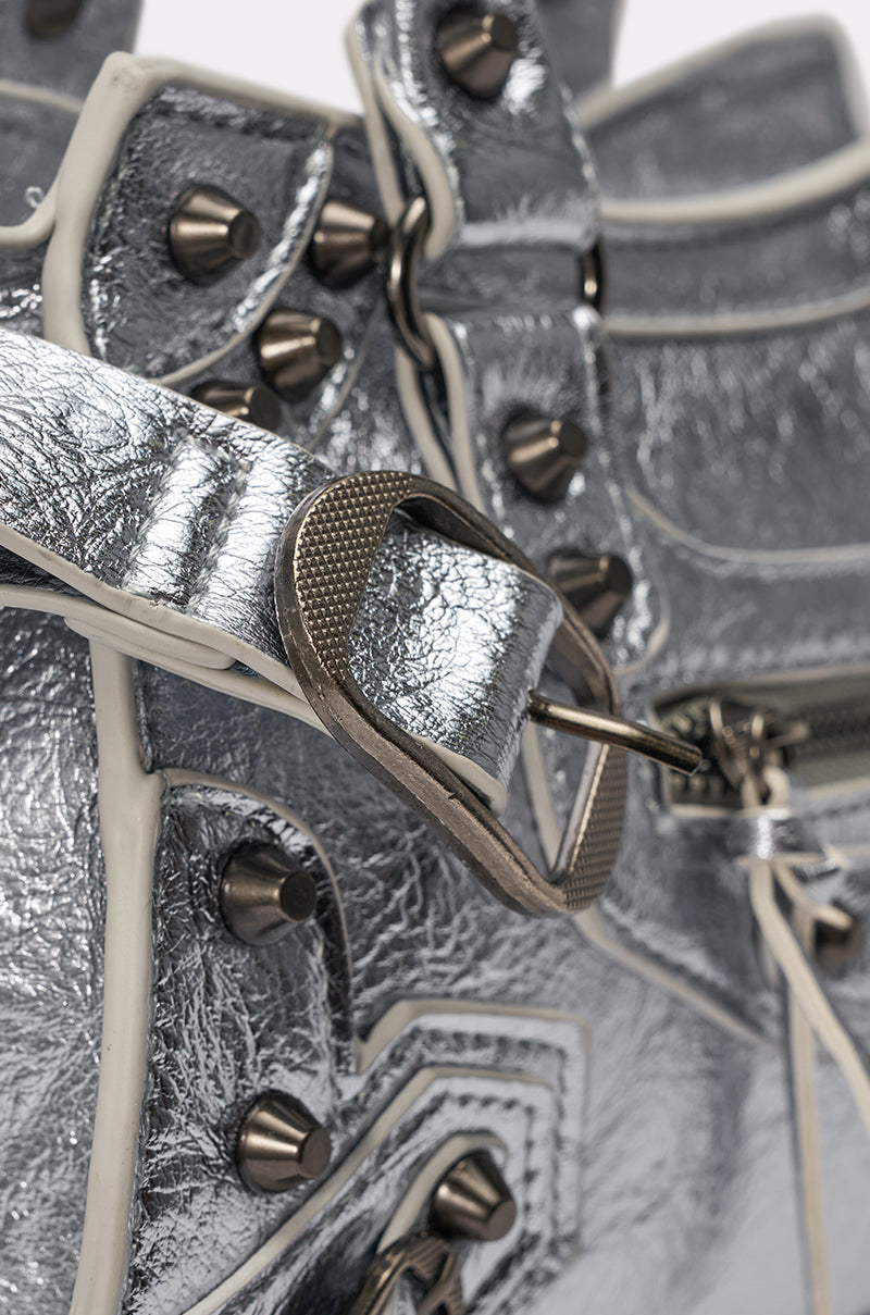 Close-up of the TO THE CITY PURSE, featuring textured faux leather, metallic finish, large silver buckle, white trim, metal studs, a removable shoulder strap, and detailed craftsmanship. 6