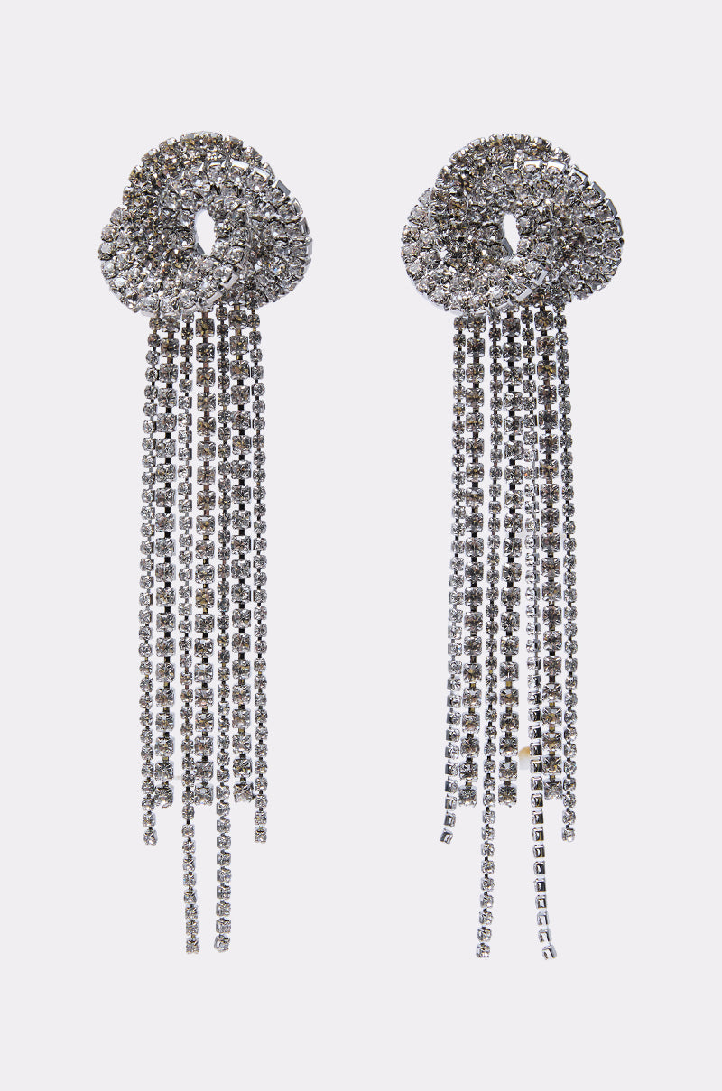 AT THE PARTY EARRING: Silver statement earrings with circular knotted tops and cascading rhinestone strands, perfect for parties. Displayed on a plain white background. 2