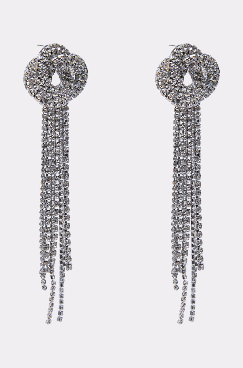 The AT THE PARTY EARRING features sparkly silver fringe with circular tops and multiple long rhinestone strands, shown against a plain light background.