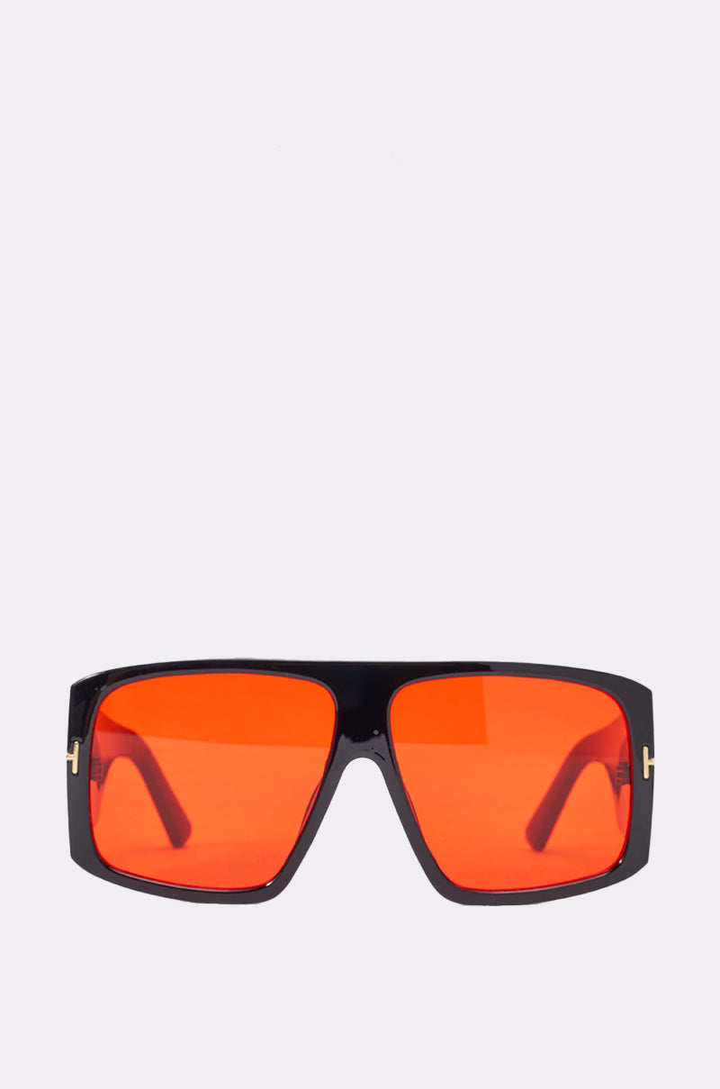 The MIND YOUR BUSINESS SUNGLASSES feature oversized retro black frames and bold red lenses, showcased on a plain light gray background.