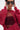 A person poses stylishly against a light background, wearing oversized black sunglasses, hoop earrings, and the OPEN FOR BUSINESS SWEATSHIRT IN BURGUNDY with rhinestone mesh paneling, holding the sunglasses with both hands.
