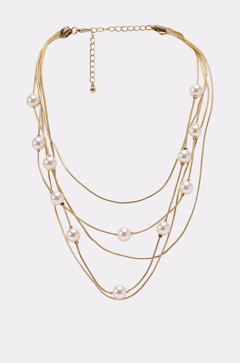 The SHES EXPENSIVE NECKLACE showcases gold-tone multi-strand chains with evenly spaced white pearls on each strand and an adjustable chain clasp at the back. 0
