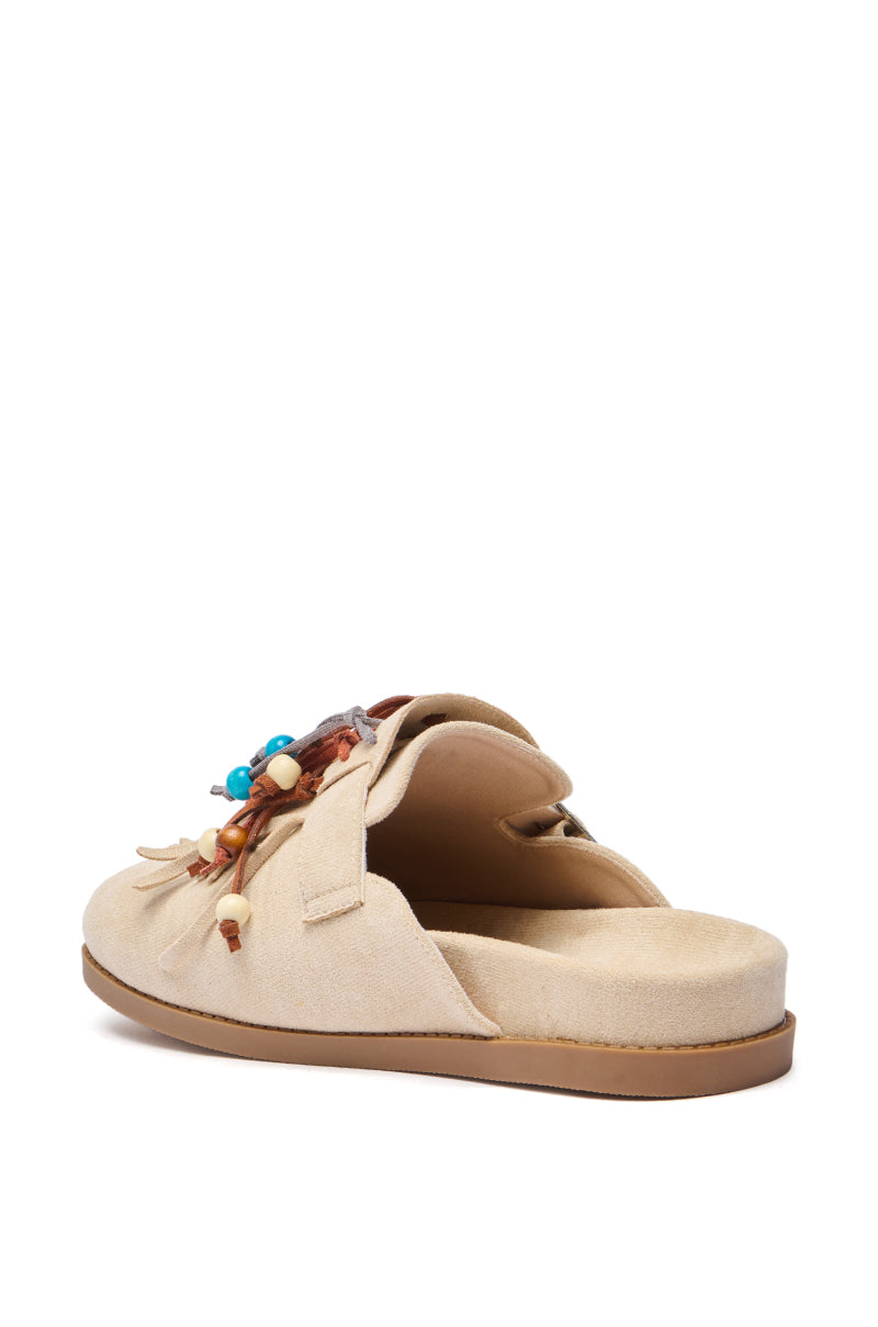 The AZALEA WANG ABEILLE BEIGE FAUX SUEDE FRINGE CLOG features a beige faux suede upper, flat rubber sole, open heel, and decorative beads with leather tassels for a casual, comfortable boho style.