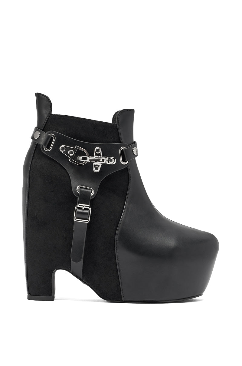 The AZALEA WANG ABYSS BLACK WEDGE PLATFORM BOOTIE is a black ankle boot with smooth leather and suede textures, a high wedge heel and platform sole, and a bold silver buckle strap detail around the ankle. 4