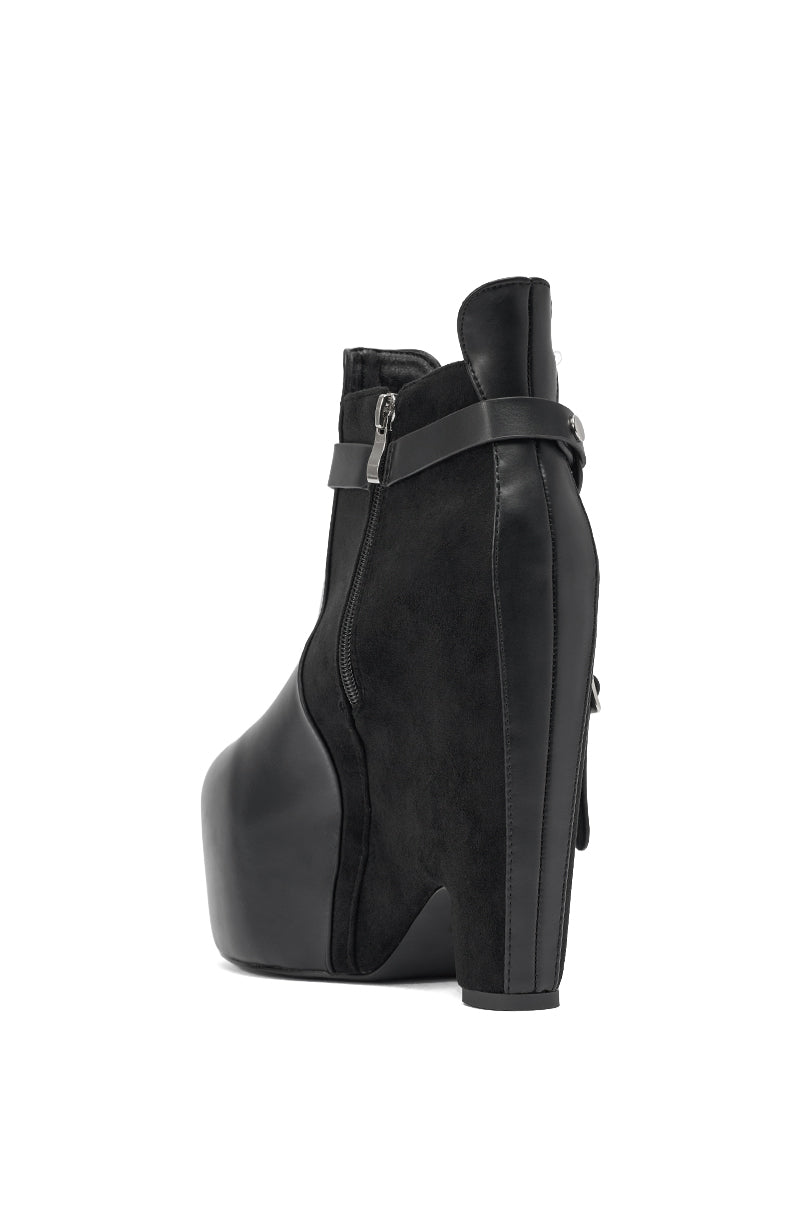 The AZALEA WANG ABYSS BLACK WEDGE PLATFORM BOOTIE features black faux leather, a bold curved platform sole, chunky heel, side zipper, and a decorative ankle strap with buckle. Smooth and suede textures combine for a striking style. 6