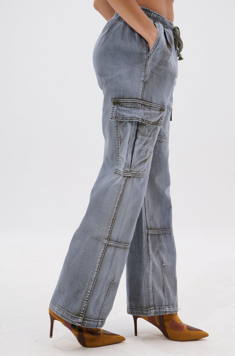 A person wears the WALLEY CARGO JOGGER high-rise denim jeans with oversized cargo pockets and brown pointed-toe heels, standing against a plain white background. 4
