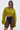 A woman models the TAKE IT EASY CROPPED BOMBER IN GREEN with black sheer high-waisted shorts, black undergarments, and sunglasses against a light gray background—a stylish outfit for transitional layering.