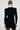 With their hair styled in a sleek bun, an individual faces away from the camera, showcasing the SUSIE MINI DRESS IN BLACK. The form-fitting dress features long sleeves that emphasize its bodycon silhouette against a plain, light-colored background.