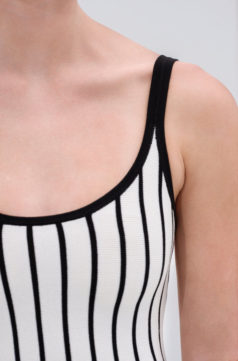 Close-up of a person wearing the LETS GET IT GOING KNIT STRIPE MIDI DRESS, featuring bold black and white stripes. The image highlights the shoulder, upper chest, and arm against a plain light background.