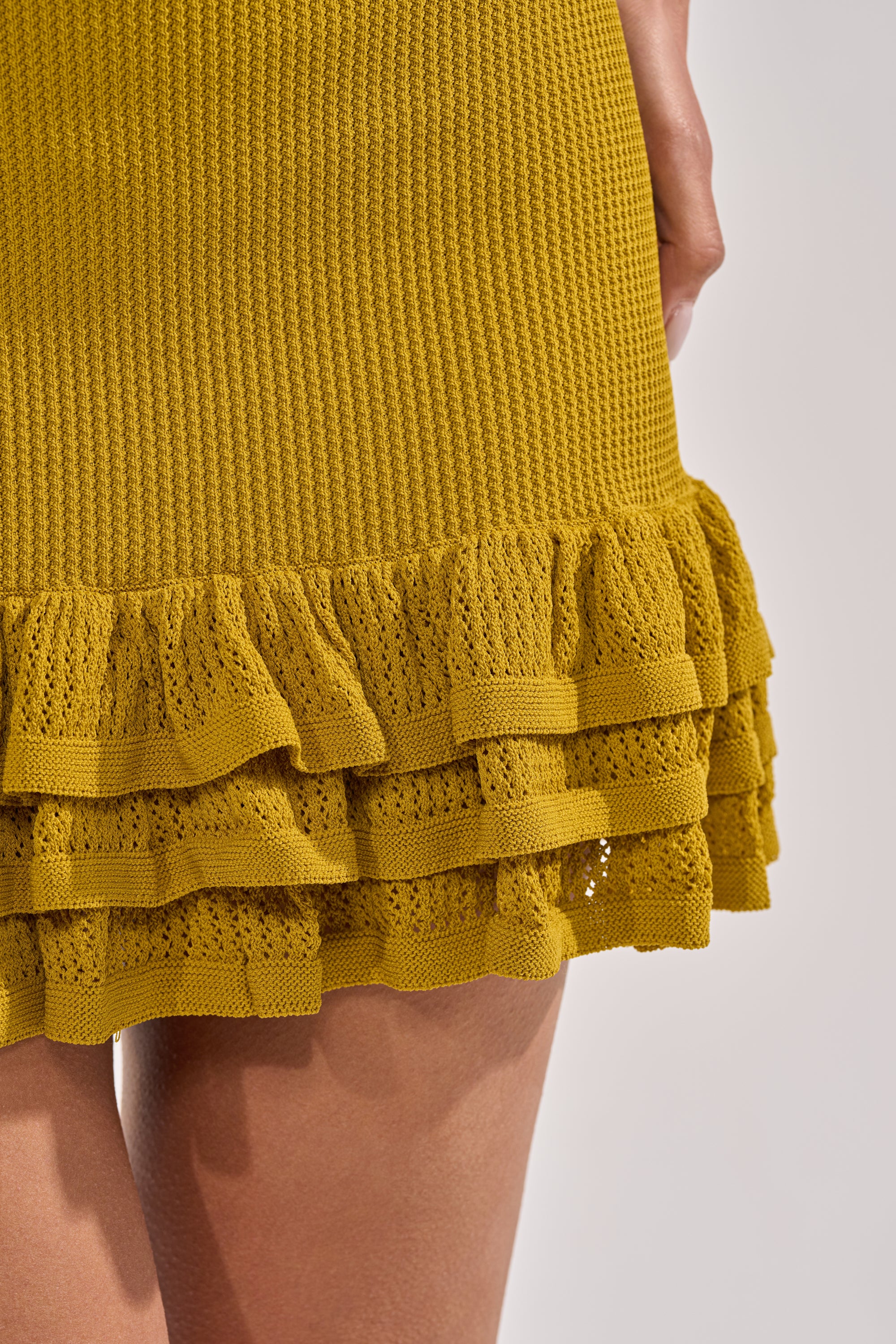 Close-up of the RUFFLE QUEEN MINI DRESS IN GREEN, featuring chartreuse knit fabric and two layers of ruffled lace near the hem, worn by a light-skinned model. 6