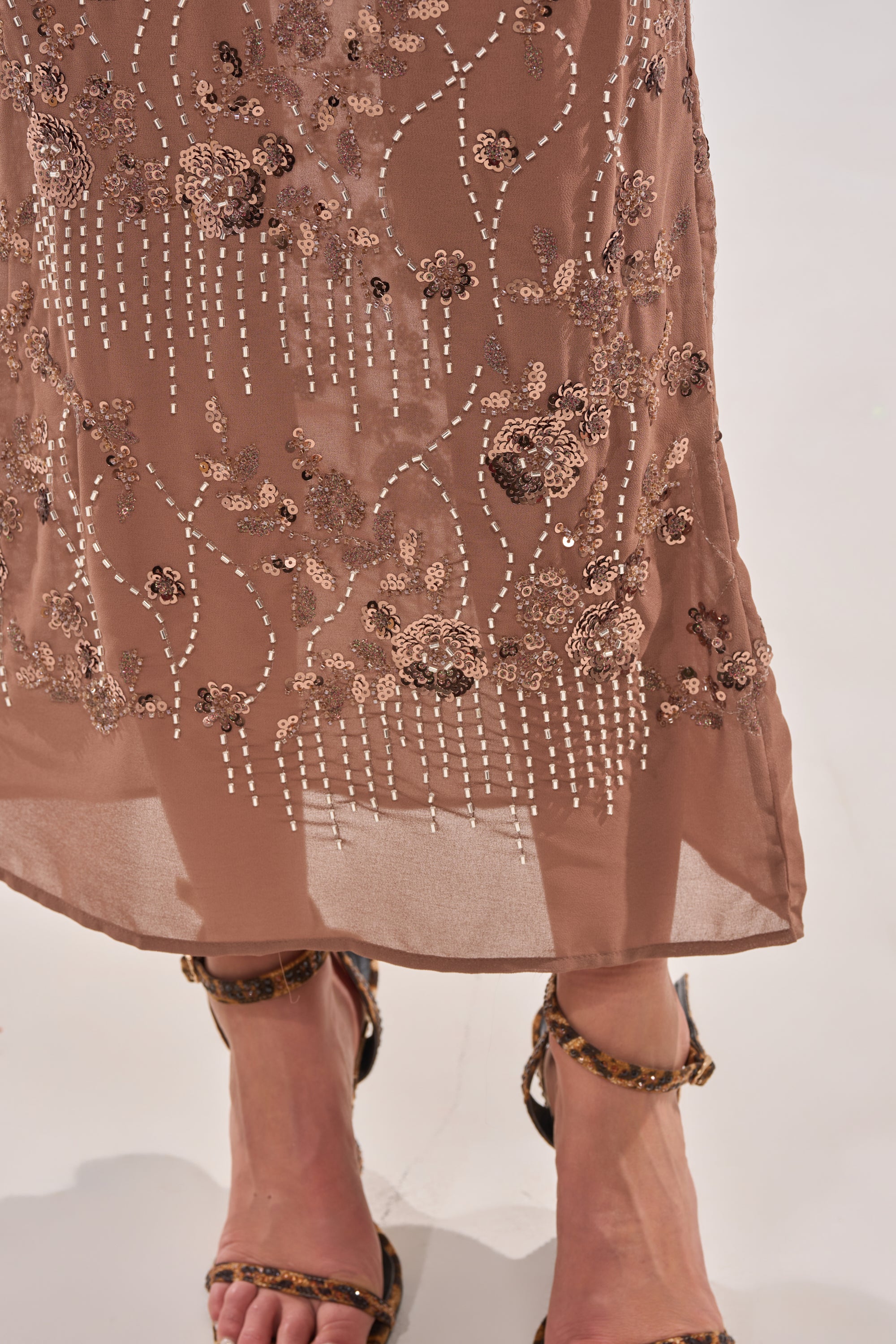 A sheer brown skirt with a beaded floral motif and sequin embroidery is styled with animal print sandals, perfect for pairing with the LOVE LETTERS EMBELLISHED MAXI DRESS. 7