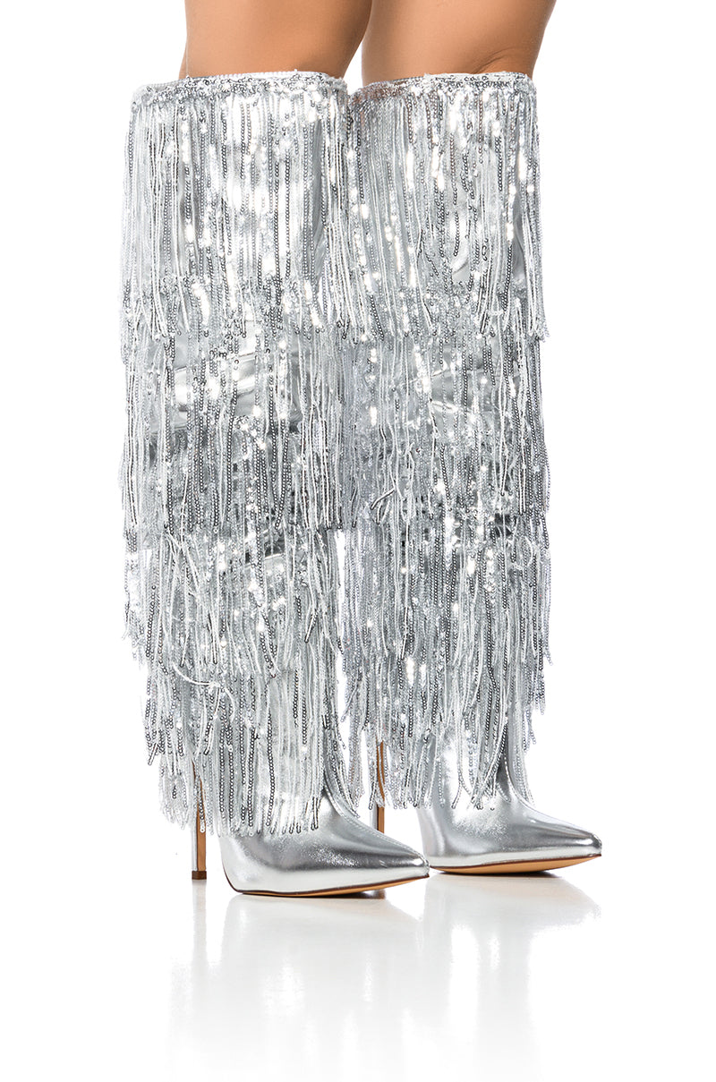 The AZALEA WANG ADRIEL SILVER FRINGE STILETTO BOOT features a glamorous design with a stiletto heel and shimmering sequin fringe details. Crafted from faux leather, these pointed-toe boots are eye-catching against a white background.
