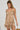 A person with long braided hair radiates confidence in the Golden Girl Chained Up Mini Dress, featuring a bodycon silhouette adorned with intricate faux gold and silver metallic chains that form a captivating shimmery pattern on its plain backdrop.