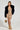 Wearing the breathtaking Gold Girl Chained Up Mini Dress, this trendsetter enhances the body-hugging design with a chic black fur jacket and gleaming gold heels. Complementing the ensemble with a matching gold handbag, their hair styled in an elegant braided updo completes the look against a simple background.