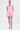 A woman poses against a white background in the ISSA LOOK MINI DRESS IN PINK, which has a corset-style bodice and flared skater skirt. She pairs it with pink statement earrings, embellished fishnet tights, lace-up heels, and wears her hair pulled back.