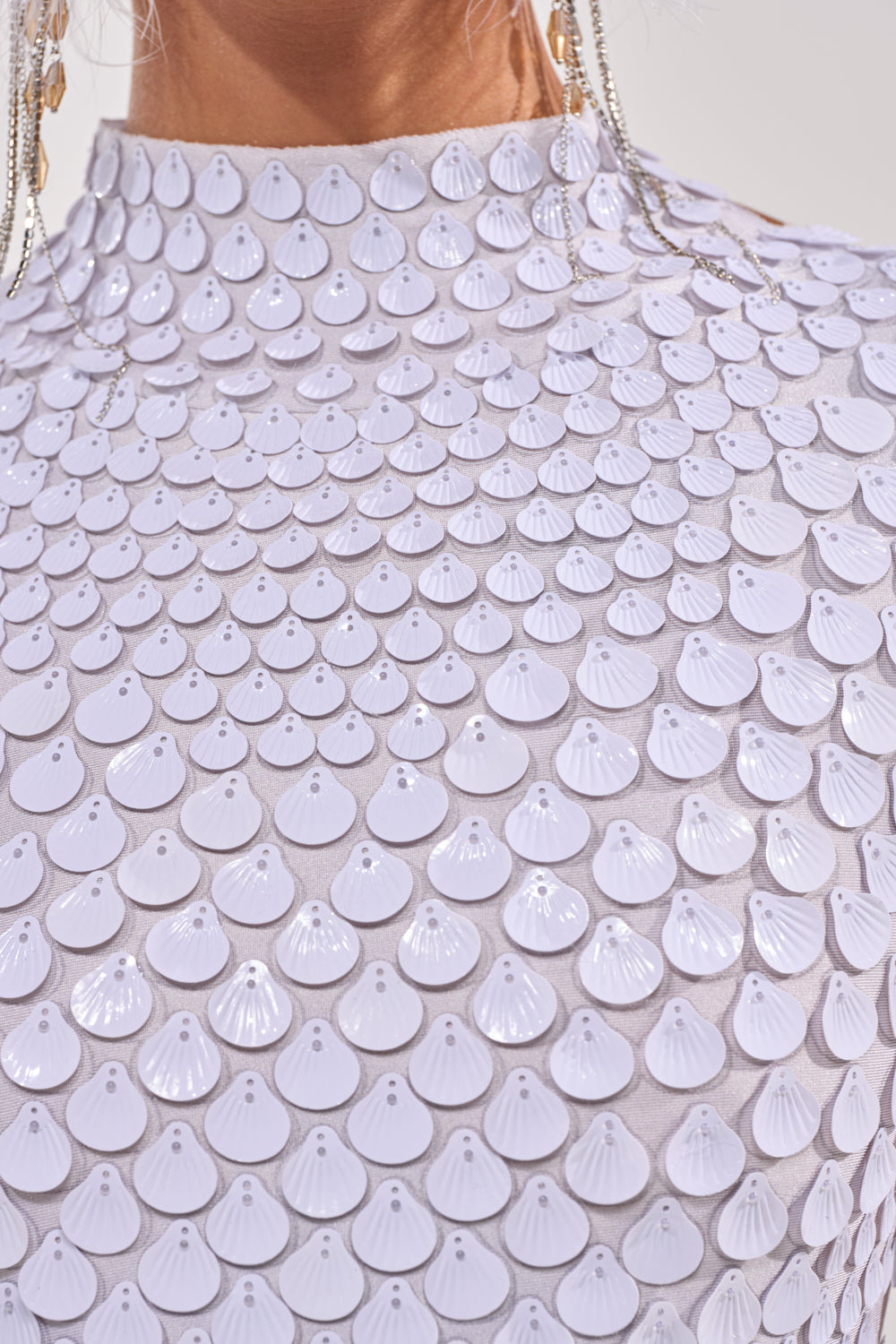 Close-up of the FAR FROM BASIC SEQUIN MINI DRESS IN WHITE, featuring neat rows of overlapping, shiny white shell-shaped sequins for a textured statement look—ideal for your next vacation. 8