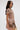 A woman with long, dark hair wears the FAR FROM BASIC SEQUIN MINI DRESS, a short-sleeved, rose gold sequin mini dress with shell embellishments, standing sideways against a plain light background.