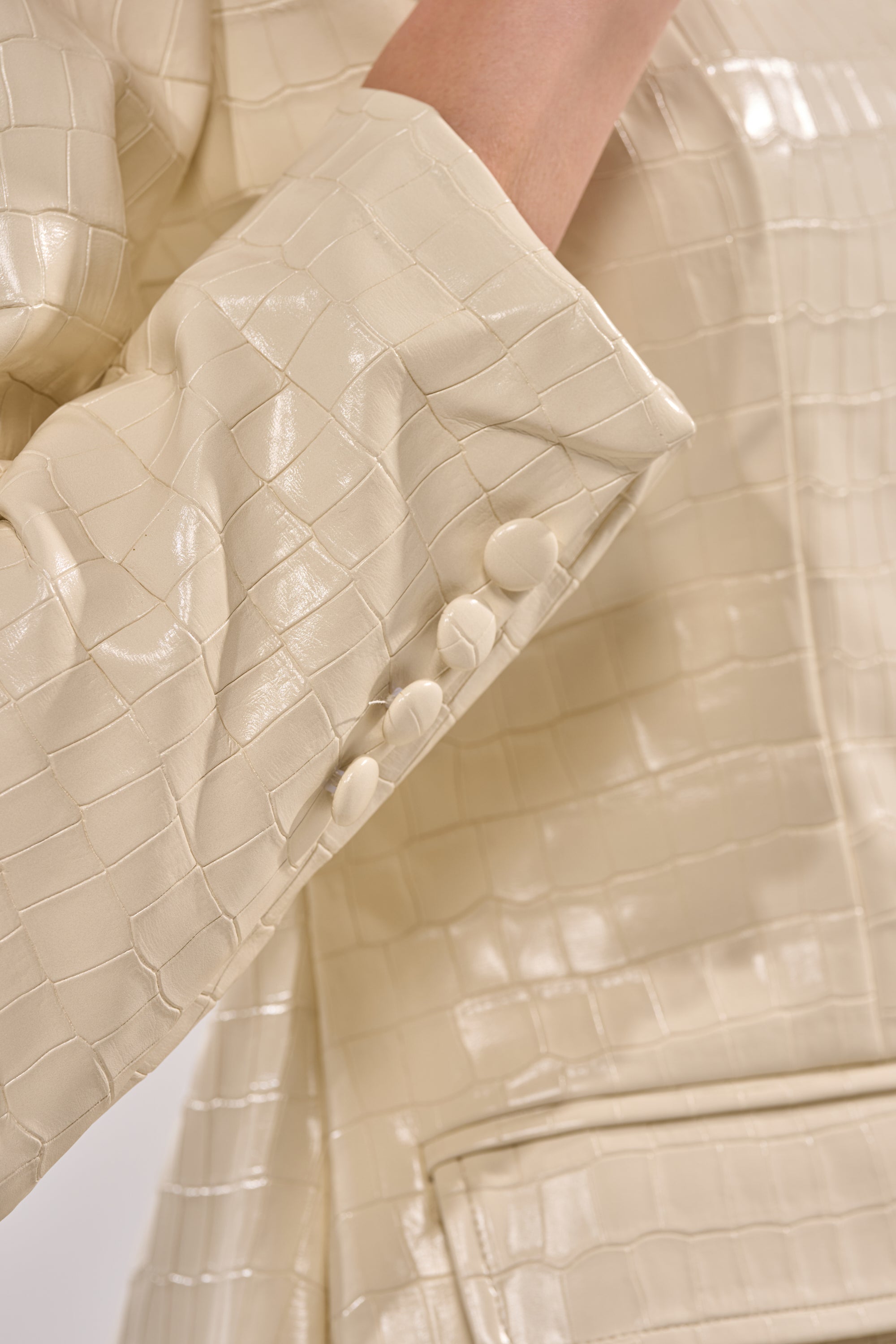 Close-up of a cream crocodile-patterned blazer sleeve with four fabric-covered buttons near the cuff and part of a pocket—perfect for pairing with the STANDING ON BUSINESS PU MINI DRESS. 9