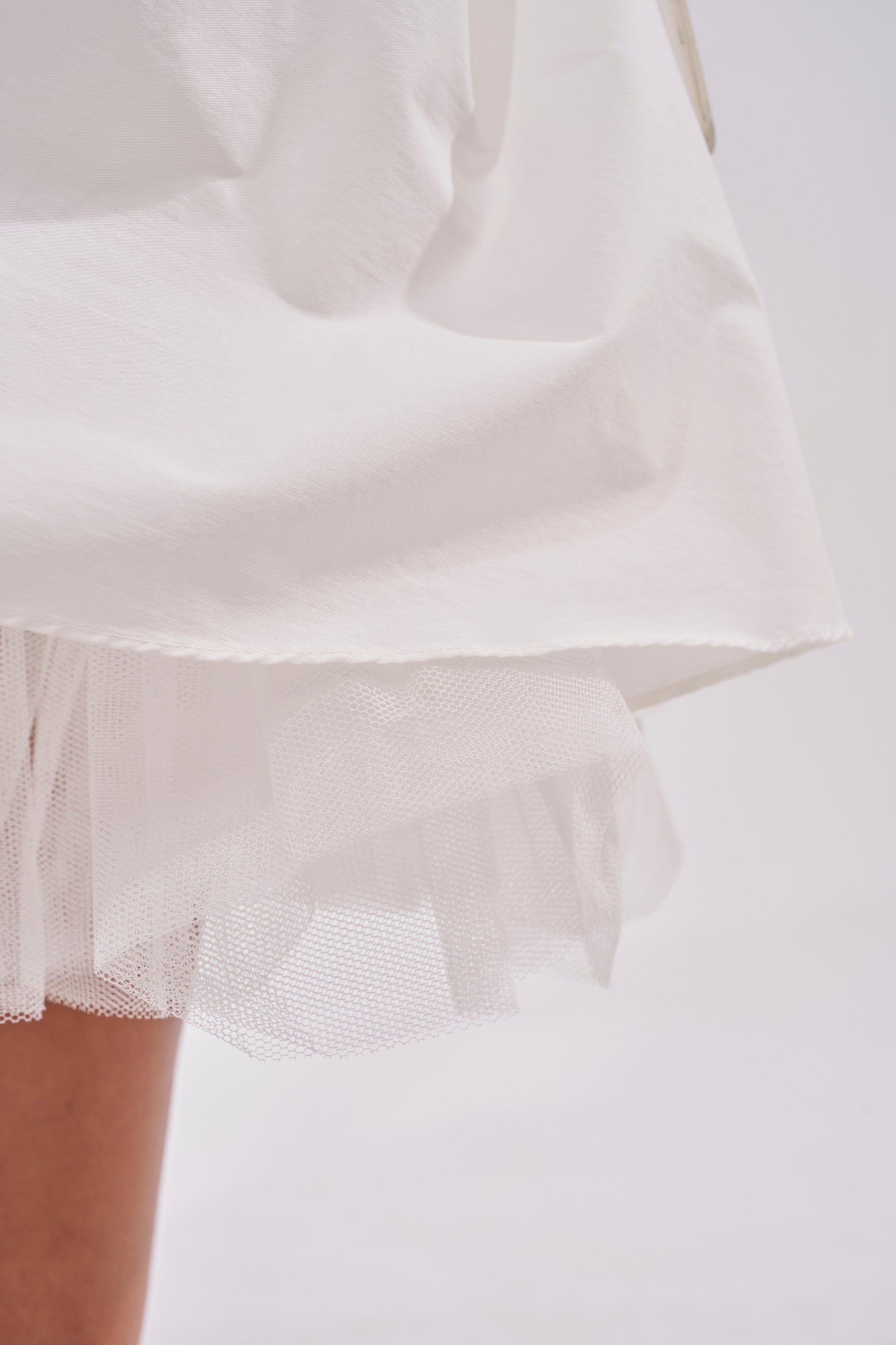 Close-up of the lower part of the SUNDAY AFTERNOON POPLIN MIDI DRESS IN WHITE, showcasing a sheer tulle layer underneath—an elegant pick for bridal events or garden parties. 8