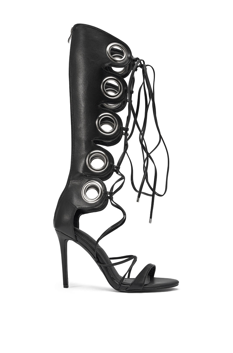 The AZALEA WANG AGATHON BLACK GLADIATOR STILETTO SANDAL features black faux leather, large silver grommets, a lace-up front, open toe, and strappy mid-calf design. 3
