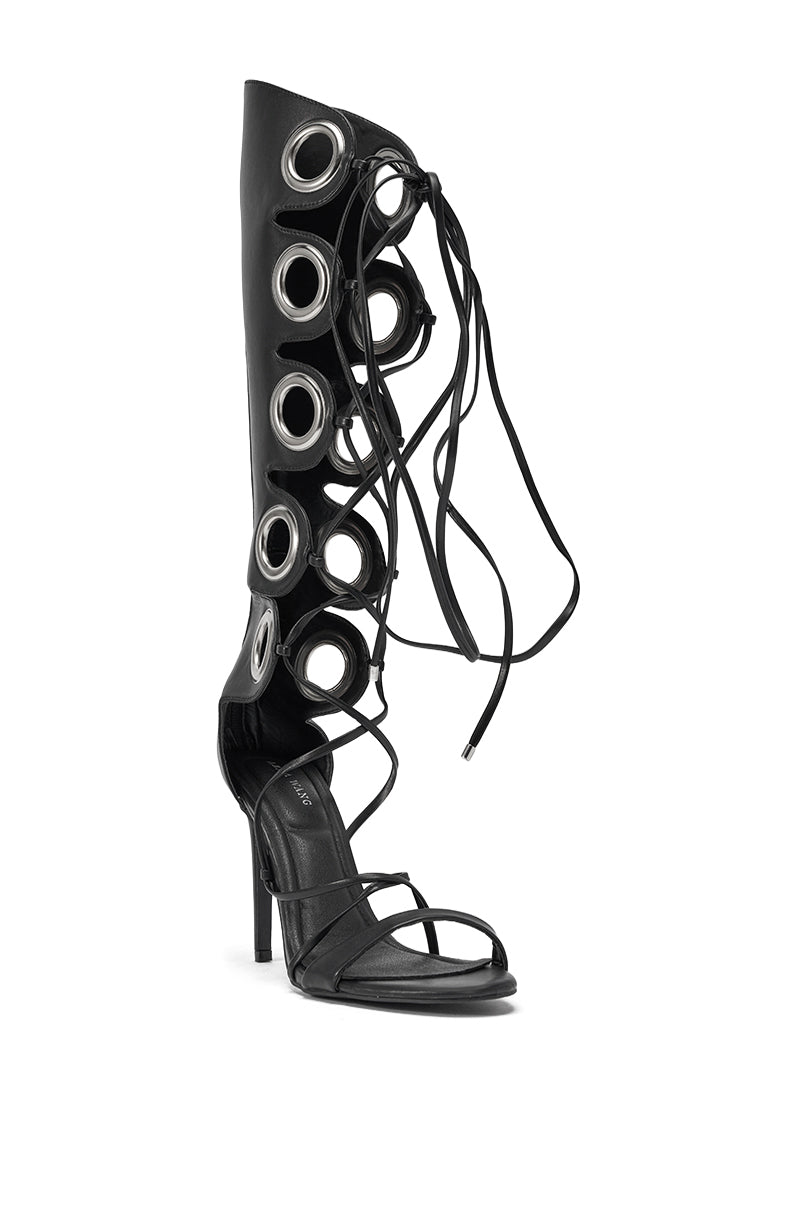The AZALEA WANG AGATHON Black Gladiator Stiletto Sandal features black faux leather, an open toe, large silver grommets, and long black crisscross laces that wrap around the leg for a striking knee-high gladiator look. 4