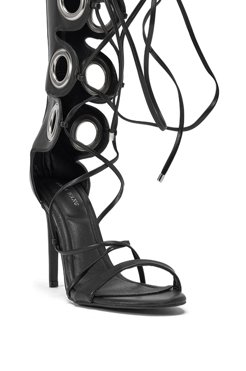 The AZALEA WANG AGATHON BLACK GLADIATOR STILETTO SANDAL features thin toe straps, large silver eyelets up the leg, and long laces that wrap around the boot for a bold, stylish look. 6